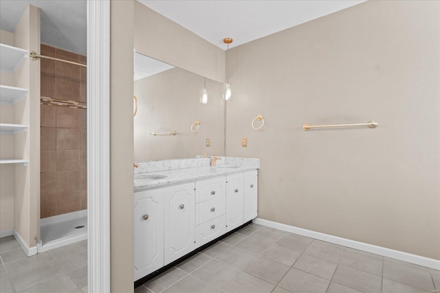 full bath featuring tile patterned floors, a stall shower, a sink, double vanity, and baseboards