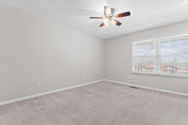 unfurnished room featuring visible vents, light colored carpet, a ceiling fan, and baseboards