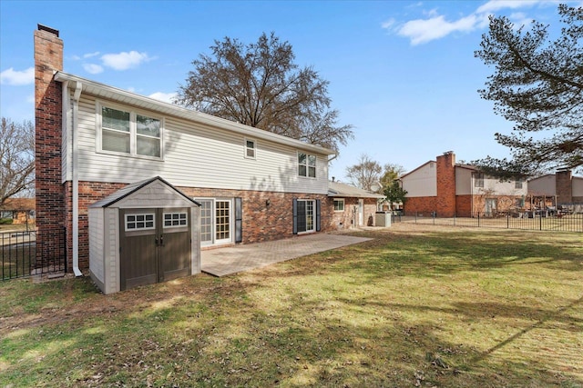 rear view of house featuring brick siding, a chimney, a fenced backyard, a yard, and a patio