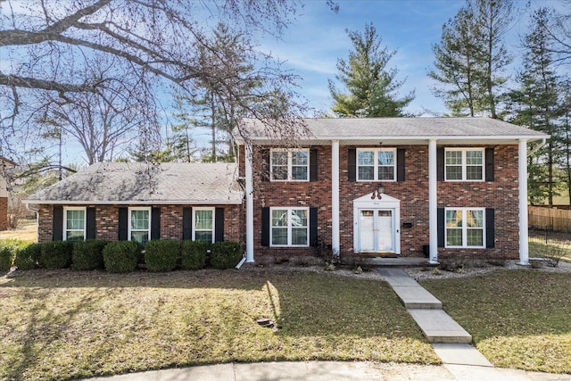 view of front of home featuring a front yard, brick siding, and roof with shingles