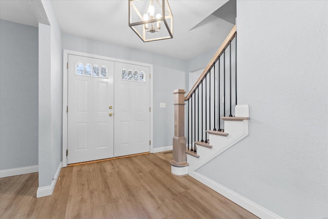 foyer with stairs, wood finished floors, and baseboards