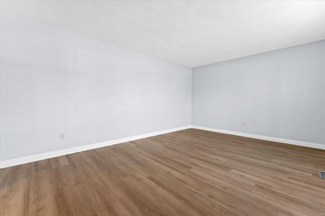 unfurnished room with visible vents, baseboards, and wood finished floors