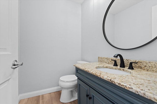 bathroom featuring vanity, toilet, wood finished floors, and baseboards