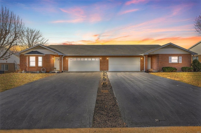 single story home featuring a garage, driveway, and brick siding