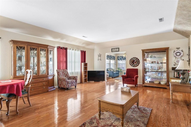 living room featuring light wood-type flooring, visible vents, and baseboards