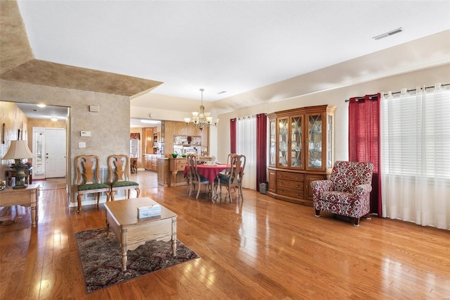 living area with hardwood / wood-style flooring, visible vents, and a notable chandelier