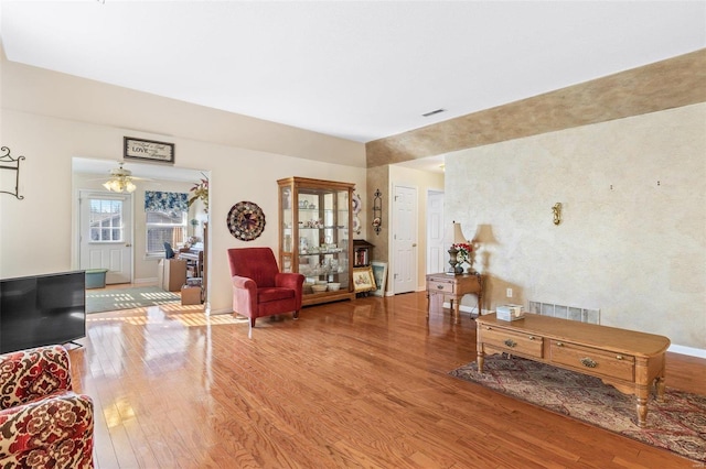 living area with wood-type flooring, visible vents, and baseboards