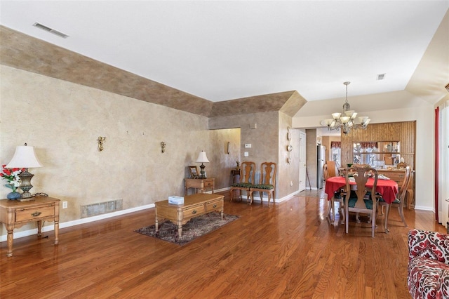 living area featuring visible vents, an inviting chandelier, and wood finished floors