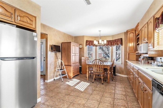 kitchen featuring stainless steel appliances, light countertops, visible vents, an inviting chandelier, and baseboards