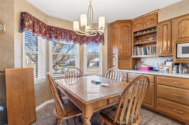 dining area featuring light tile patterned floors, baseboards, and a chandelier