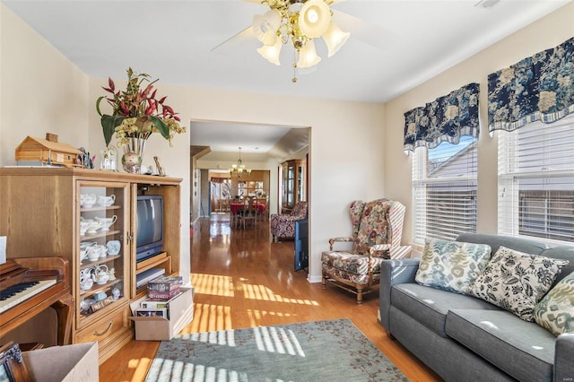 living room featuring ceiling fan with notable chandelier and wood finished floors