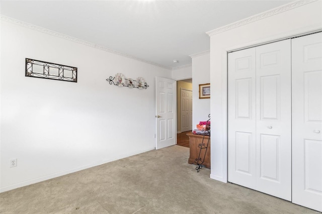 bedroom featuring a closet, light colored carpet, crown molding, and baseboards