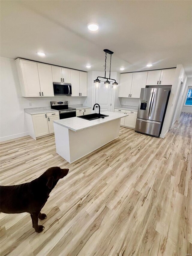 kitchen featuring light wood finished floors, white cabinetry, stainless steel appliances, and a sink