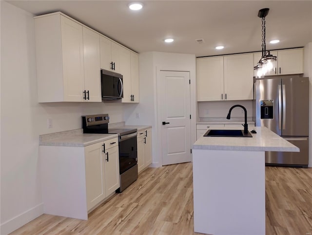 kitchen with a sink, light wood-type flooring, a center island with sink, and stainless steel appliances