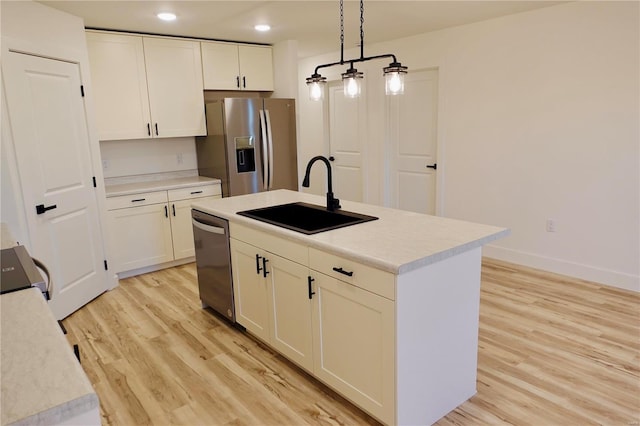 kitchen with white cabinets, light wood-style floors, appliances with stainless steel finishes, and a sink