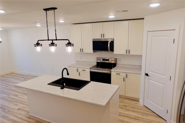 kitchen featuring light wood-style flooring, a sink, light countertops, white cabinets, and appliances with stainless steel finishes