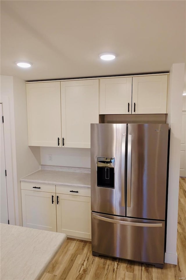 kitchen with recessed lighting, stainless steel fridge with ice dispenser, light countertops, white cabinets, and light wood-style floors