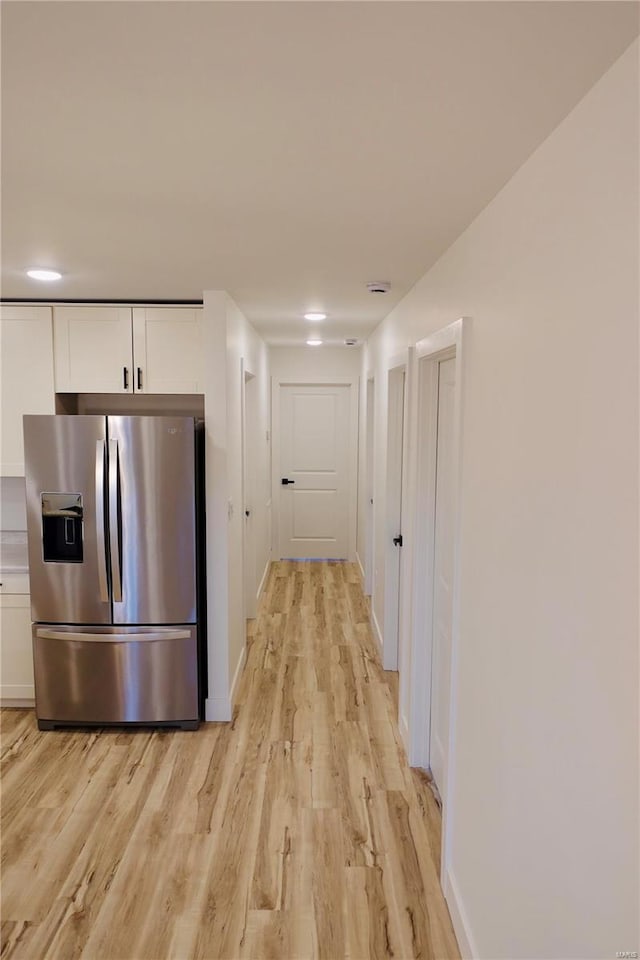 hallway featuring light wood-style flooring and baseboards