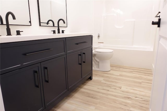 bathroom featuring double vanity, toilet, shower / bathing tub combination, and wood finished floors