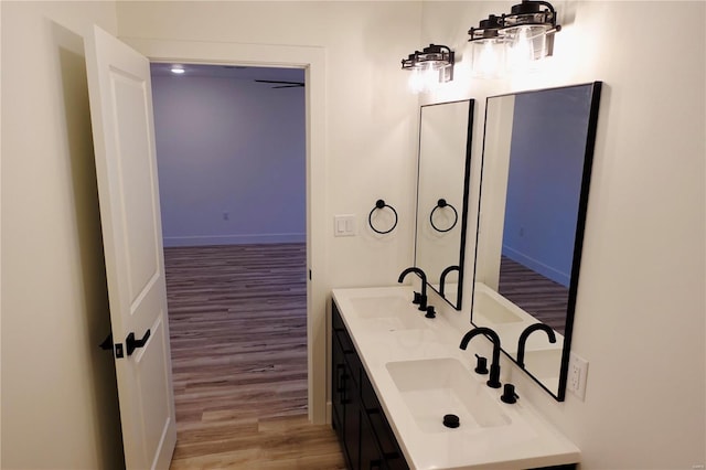 bathroom featuring double vanity, wood finished floors, and a sink