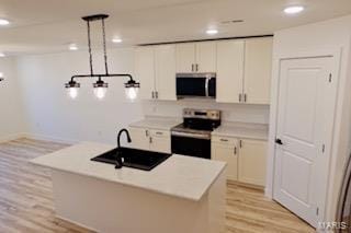 kitchen with white cabinetry, light countertops, light wood-style flooring, and stainless steel appliances