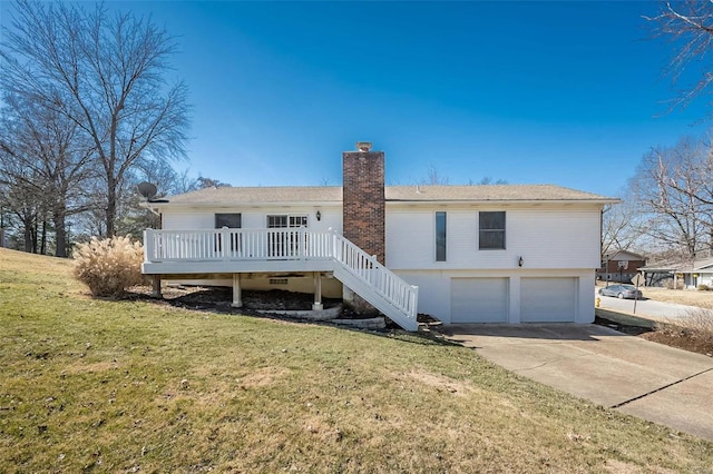 back of property with a garage, a chimney, stairs, and a lawn