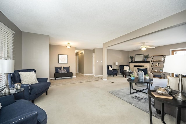 living area featuring a textured ceiling, ceiling fan, carpet floors, a fireplace, and baseboards