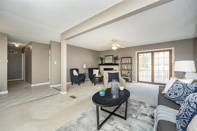 living room featuring carpet, a fireplace, baseboards, and a ceiling fan