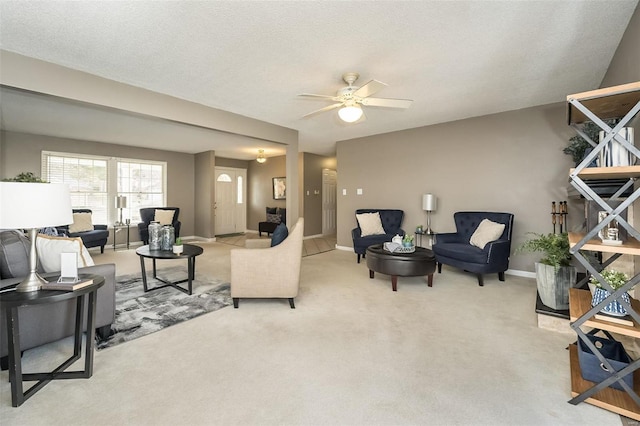 carpeted living area featuring a ceiling fan, baseboards, and a textured ceiling