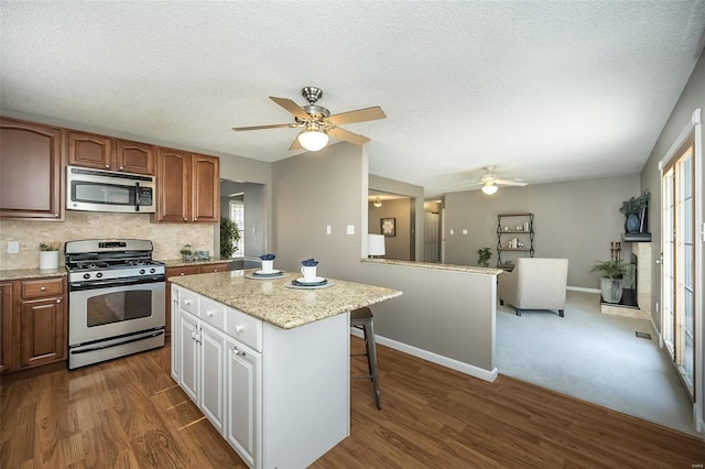 kitchen with tasteful backsplash, a kitchen island, a kitchen breakfast bar, dark wood-style flooring, and stainless steel appliances