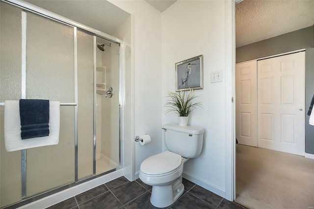 bathroom featuring a textured ceiling, toilet, baseboards, tile patterned floors, and a stall shower