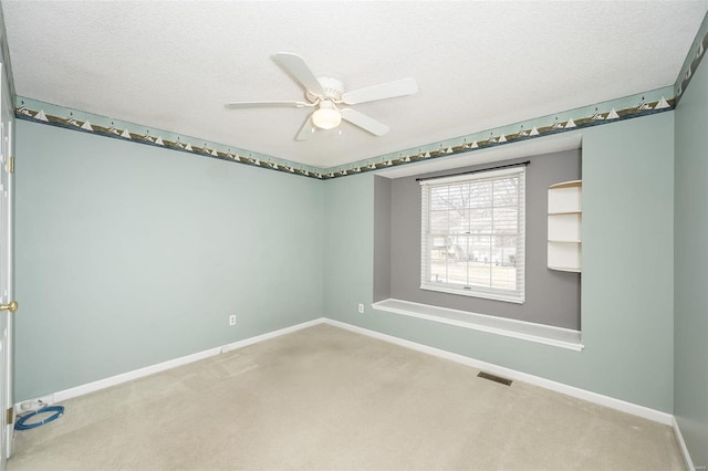 unfurnished room featuring a textured ceiling, carpet flooring, visible vents, and baseboards