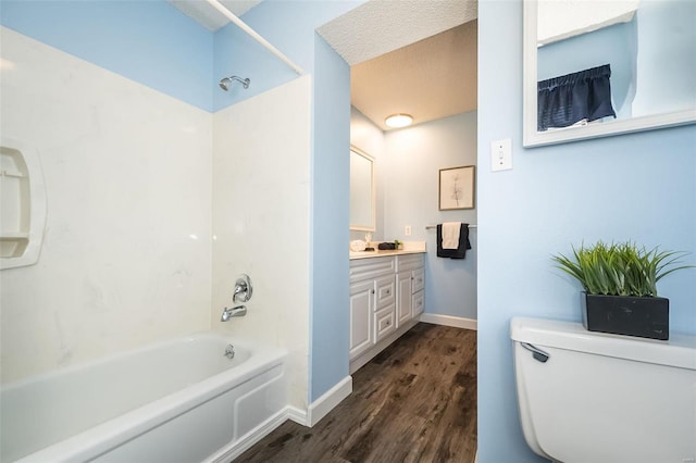 bathroom featuring baseboards, toilet, wood finished floors, tub / shower combination, and vanity