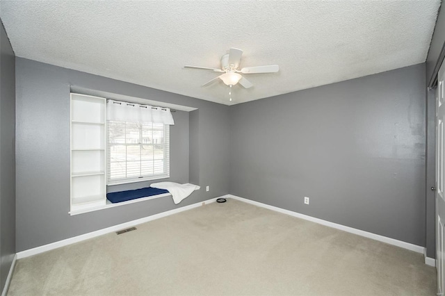 carpeted empty room with visible vents, ceiling fan, a textured ceiling, and baseboards