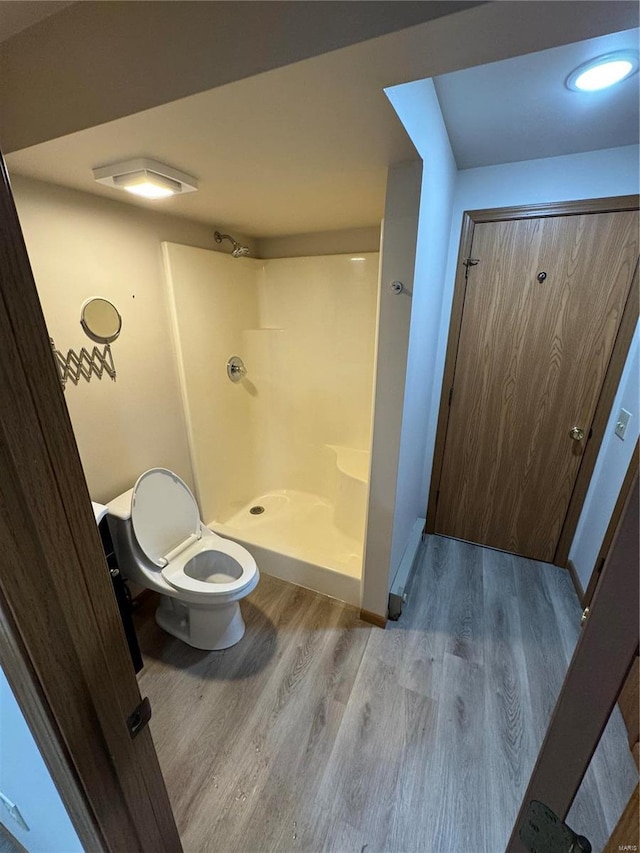 bathroom featuring a stall shower, toilet, and wood finished floors