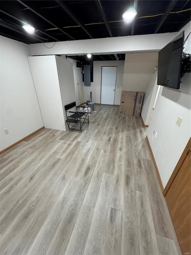 finished basement with electric panel, baseboards, and wood finished floors