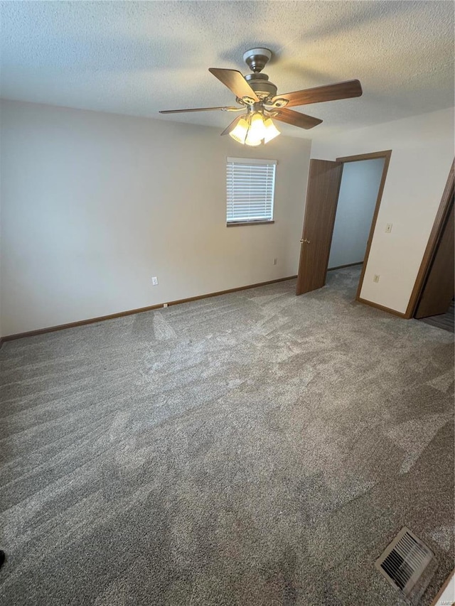 empty room with baseboards, visible vents, ceiling fan, a textured ceiling, and carpet flooring