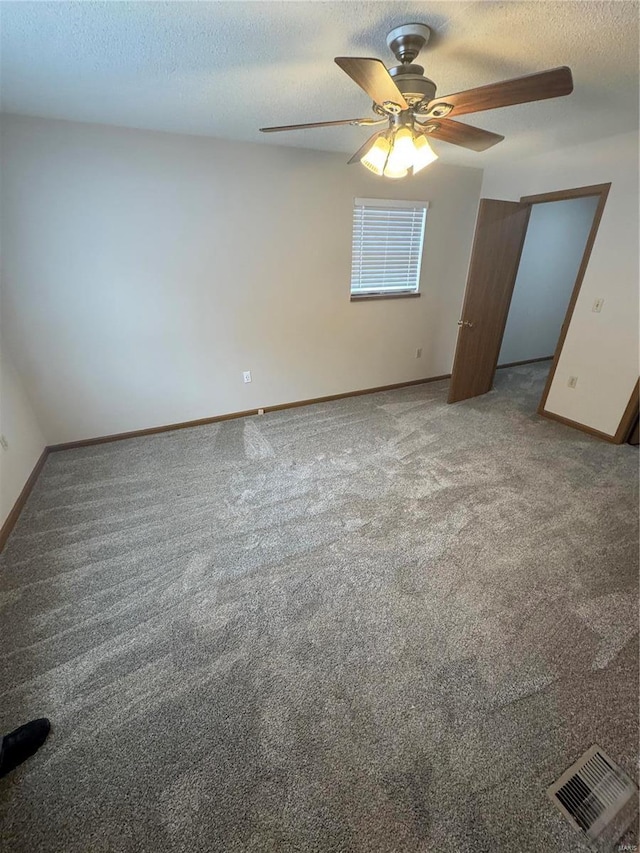 empty room featuring baseboards, visible vents, ceiling fan, carpet, and a textured ceiling