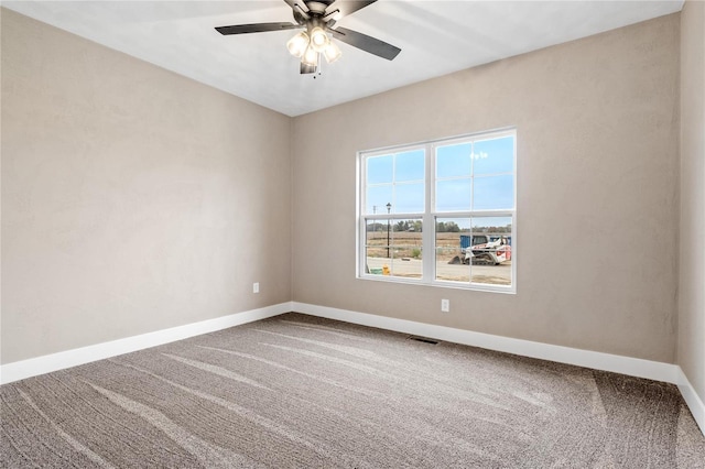 carpeted spare room featuring visible vents, baseboards, and a ceiling fan