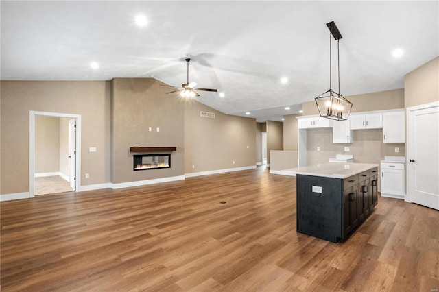 kitchen featuring a glass covered fireplace, a center island, white cabinetry, light wood finished floors, and ceiling fan