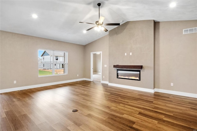 unfurnished living room featuring a glass covered fireplace, wood finished floors, and visible vents