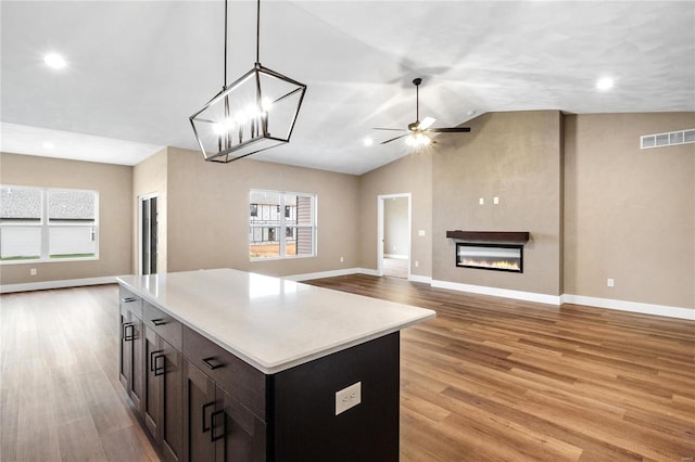 kitchen featuring visible vents, open floor plan, light countertops, light wood-type flooring, and a glass covered fireplace