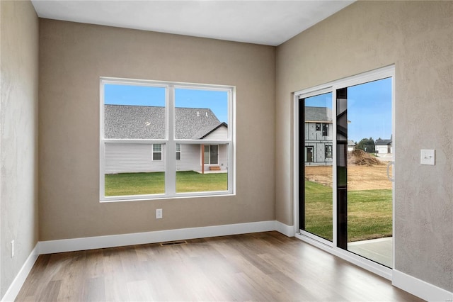 empty room with visible vents, plenty of natural light, and wood finished floors