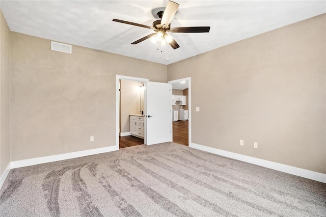 unfurnished bedroom featuring a ceiling fan, baseboards, visible vents, dark carpet, and connected bathroom