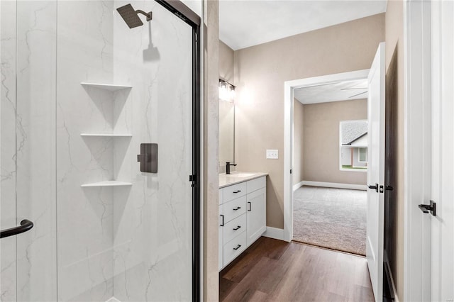 bathroom featuring a marble finish shower, vanity, baseboards, and wood finished floors