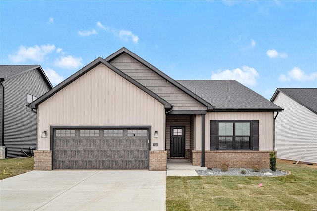 view of front of property featuring a front yard, driveway, roof with shingles, an attached garage, and brick siding