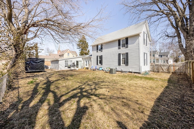 rear view of house featuring a yard, cooling unit, a fenced backyard, and a gate