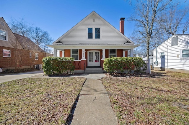 bungalow-style house with a porch, french doors, a chimney, and central air condition unit