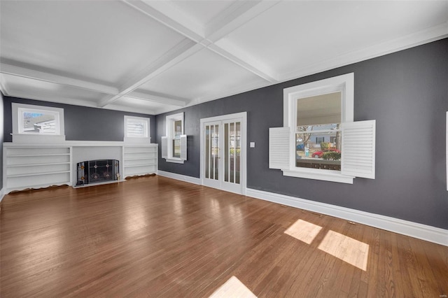 unfurnished living room featuring a fireplace with flush hearth, baseboards, wood finished floors, and beamed ceiling