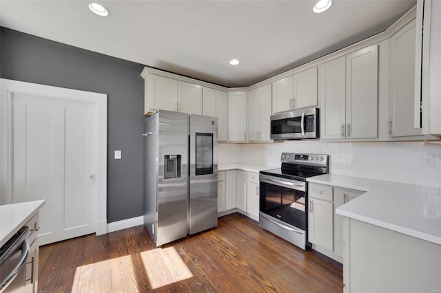 kitchen featuring decorative backsplash, stainless steel appliances, dark wood finished floors, and light countertops